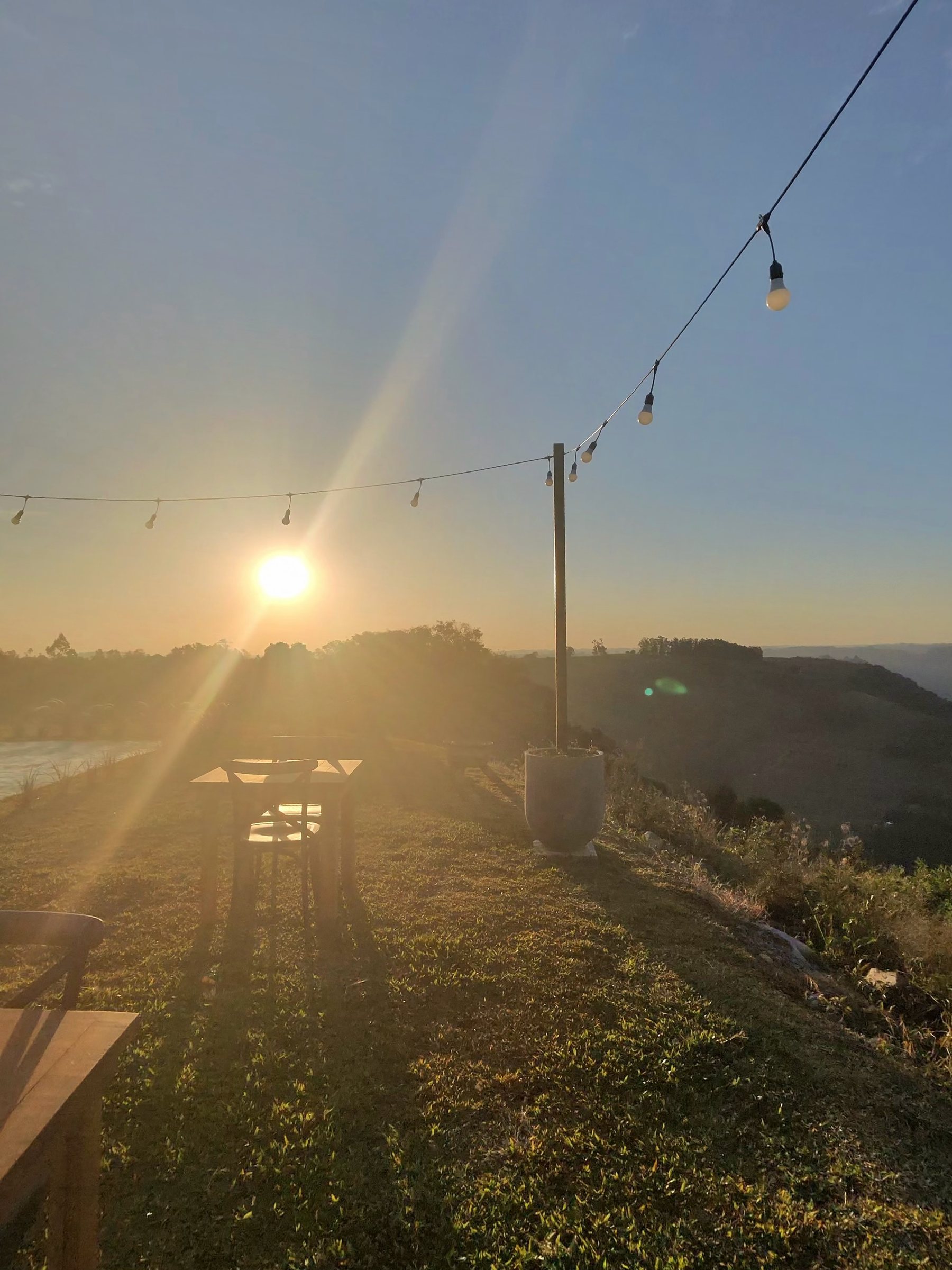 Pôr do sol sobre o mar de nuvens no penhasco, com as mesas e o varal de luzes
