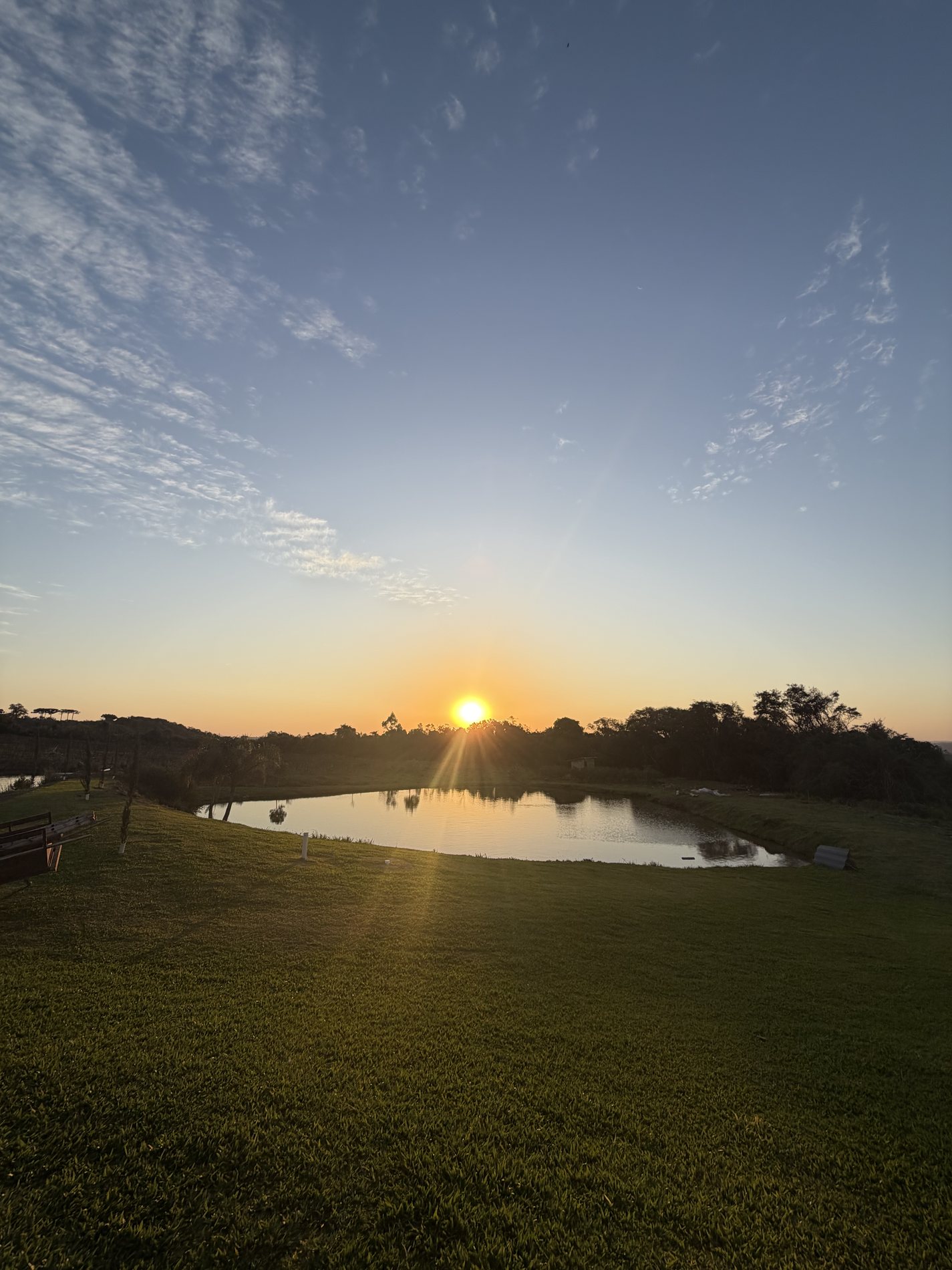 O sol se pondo sobre o lago e as colinas da serra